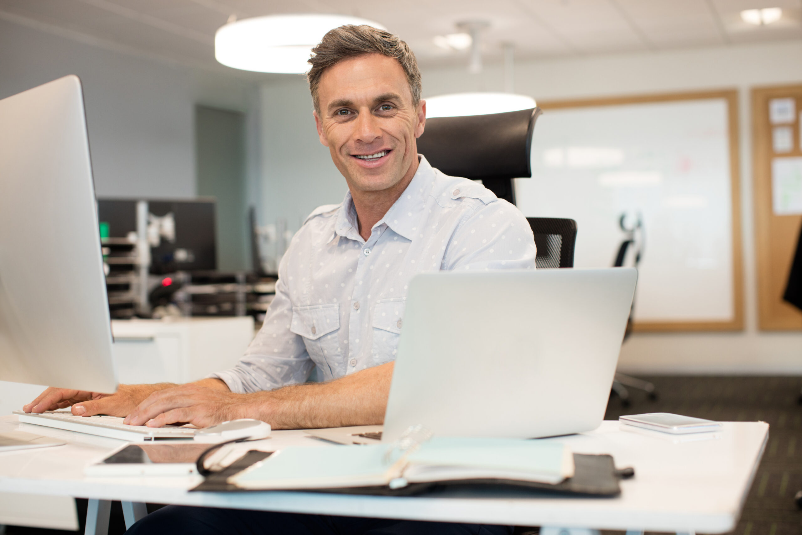 Happy business owner sitting at desk with laptop — Join HVAC Success service business support